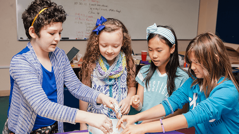 A group of children playing with oobleck during a break camp.