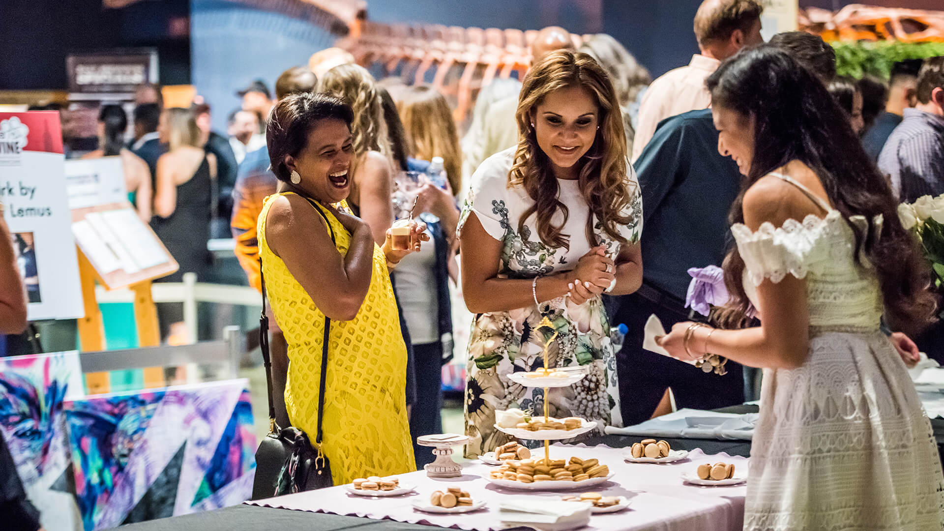 Women sampling macarons in the DinoDigs exhibit.