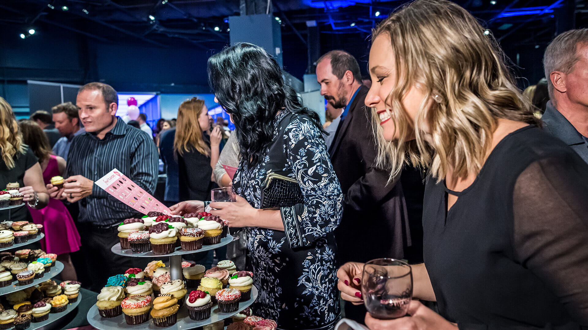 Guests picking up cupcakes at a food table.