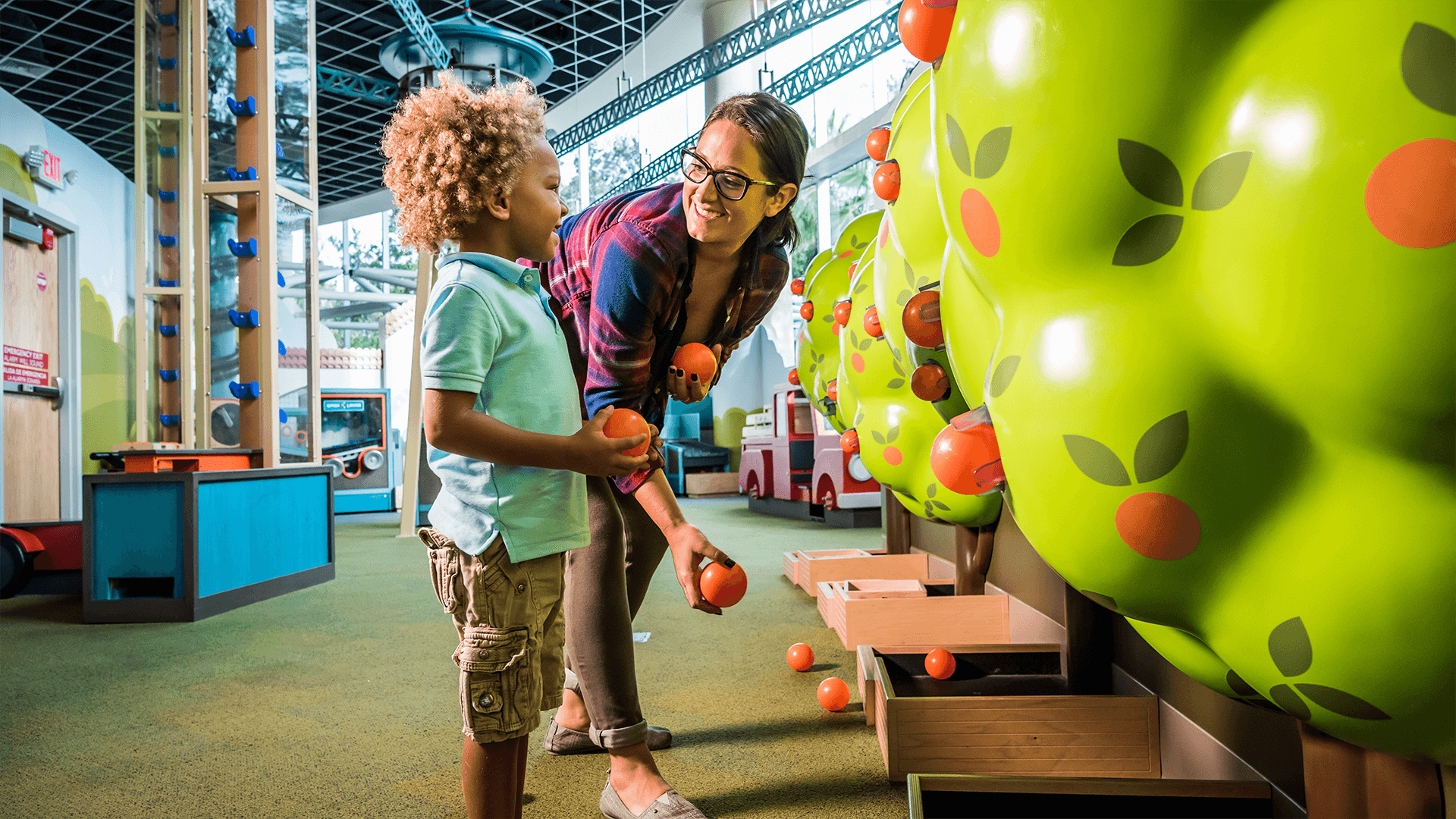 A child and caretaker pick oranges together in the KidsTown orange grove.