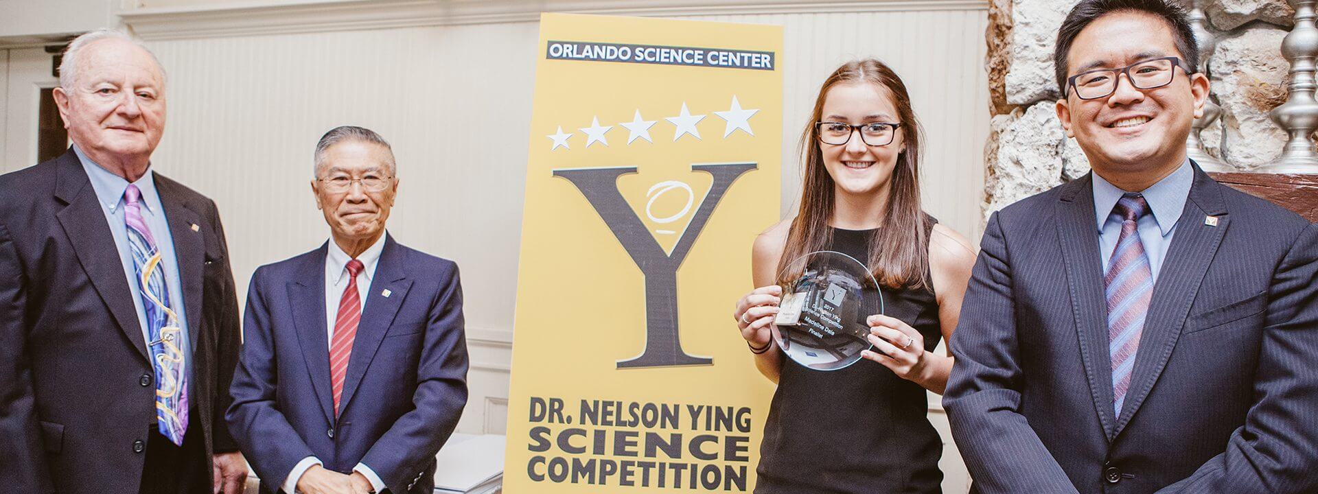 A high school student smiles with her award at the Dr. Nelson Ying Science Competition.