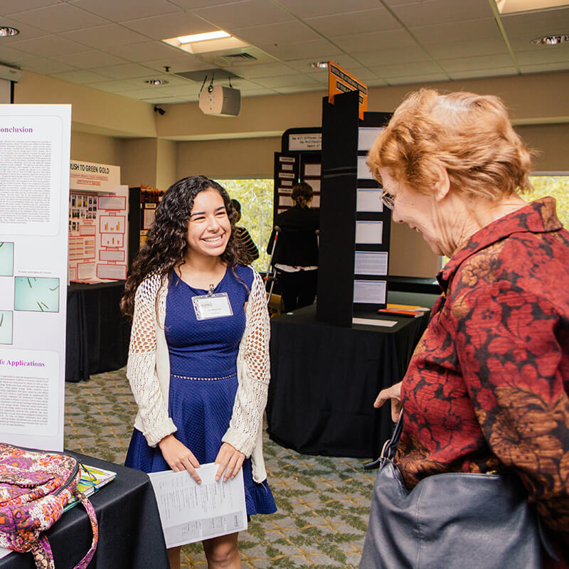 A student showing her research project to a judge at the Lockheed Martin Science Challenge.