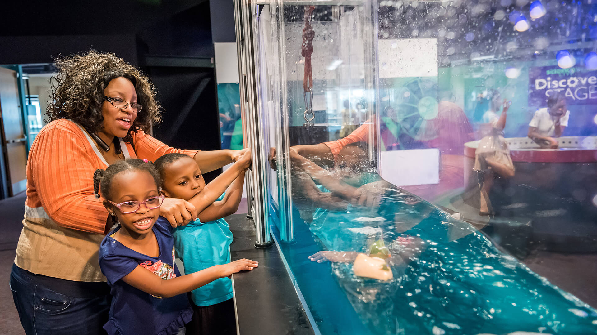 Children and their mom operate the wave simulator in the Our Planet exhibit.