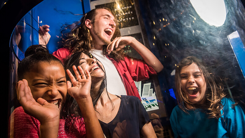 A group of guests laughing in the hurricane simulator.
