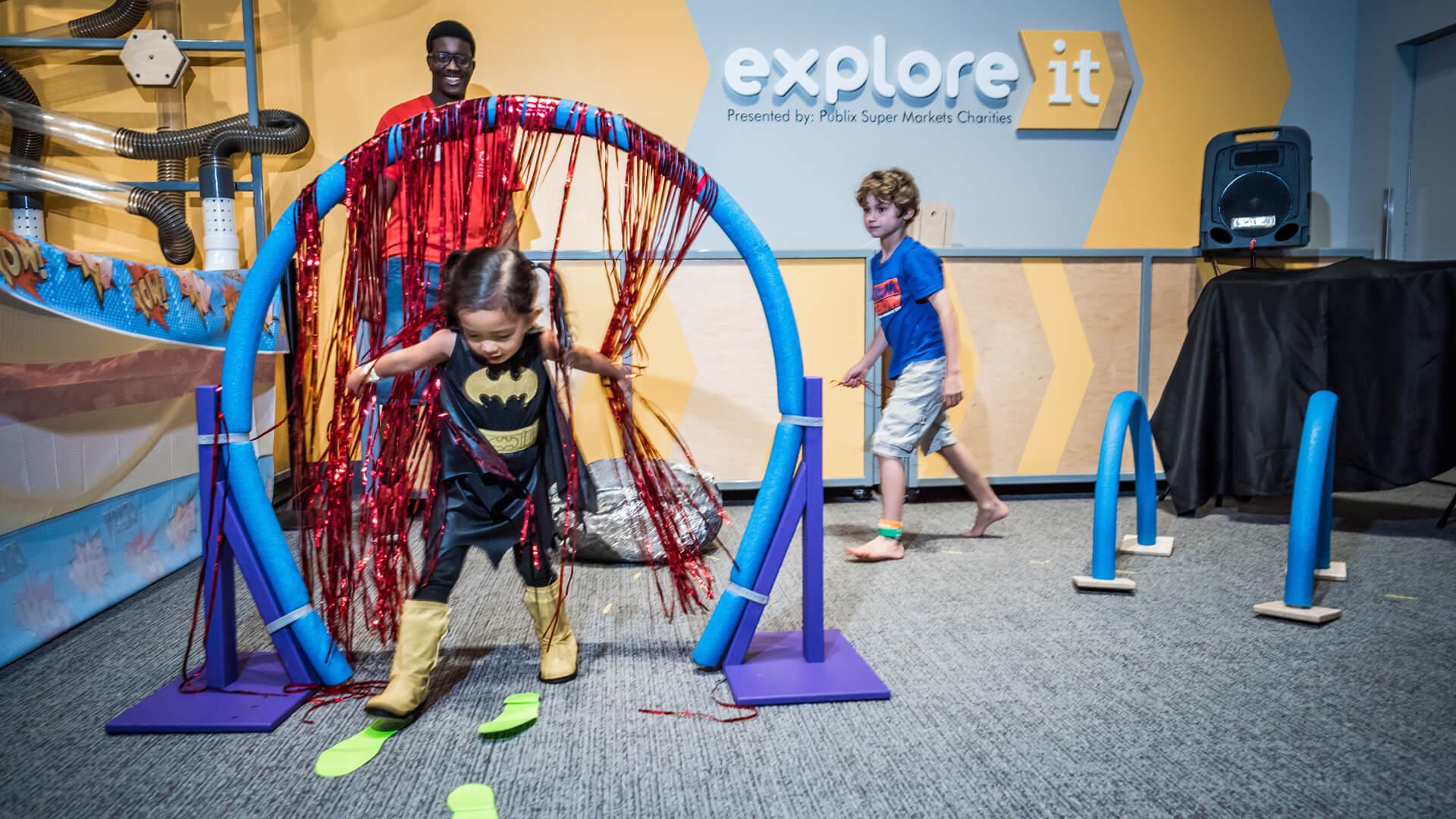 Child in Batgirl costume navigating obstacle course at Science Center