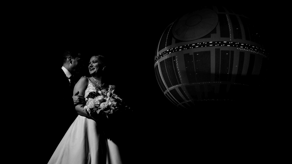 Black and white photo of newlywed couple posing in front of Death Star at their Orlando Science Center wedding