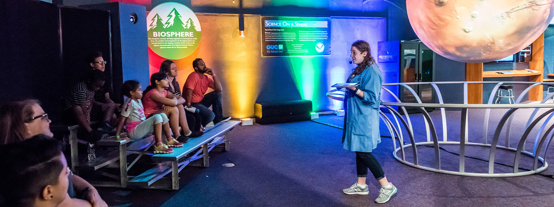 Group of seated guests learning about astronomy during presentation at Science on a Sphere.