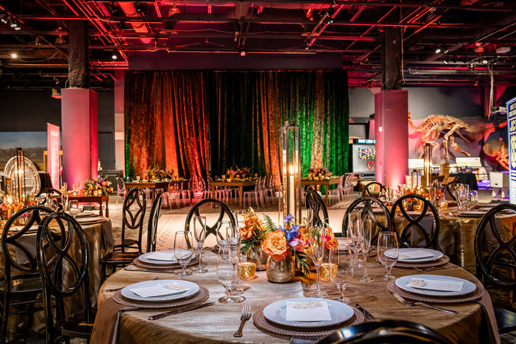 Unveil-Showcase-Event3_1080x720 Wedding setup in DinoDigs exhibit featuring blue lights and beautiful table display.