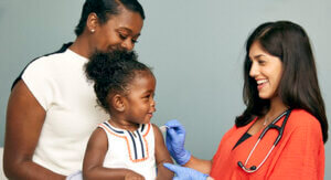 A mother and her toddler daughter prep for a vaccine with a nurse