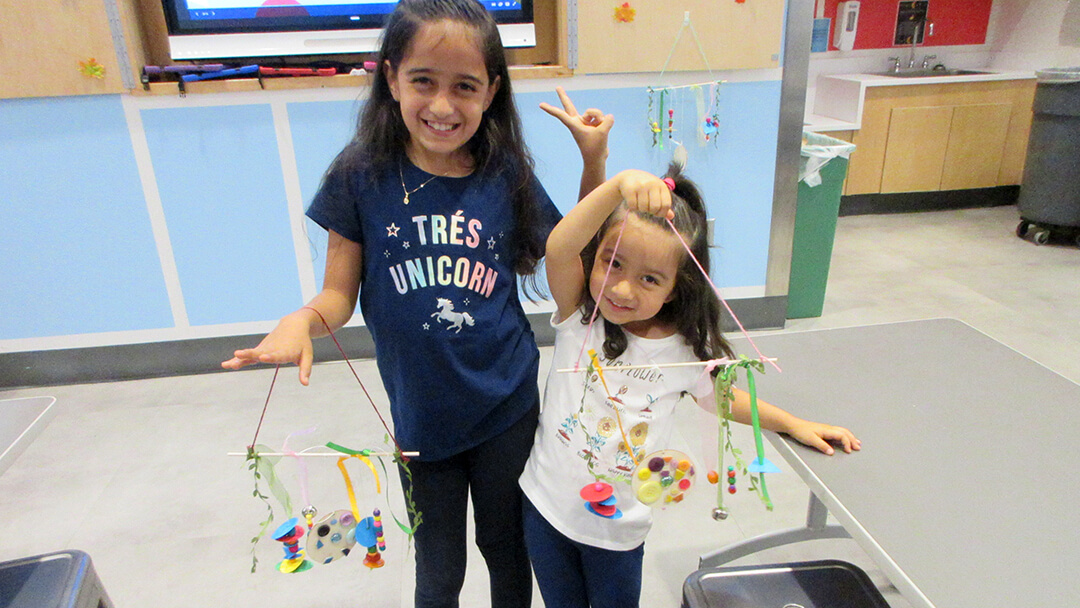 Two kids show off the mobiles they made in Mosaics, Mobiles, Math workshop.