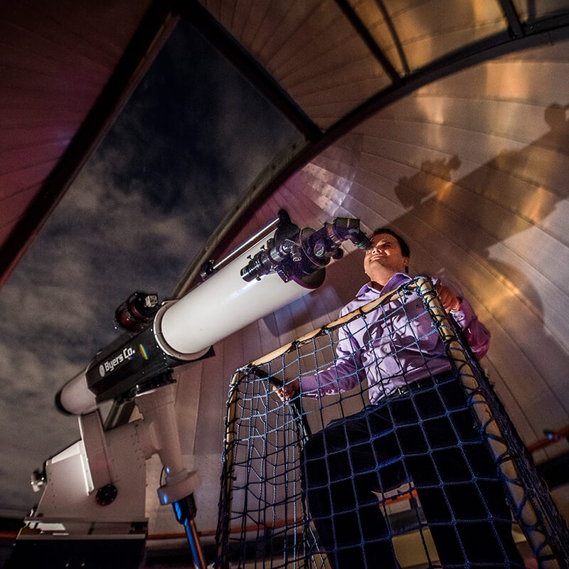 a man looking throught a giant telescope in orlando science center's observatory