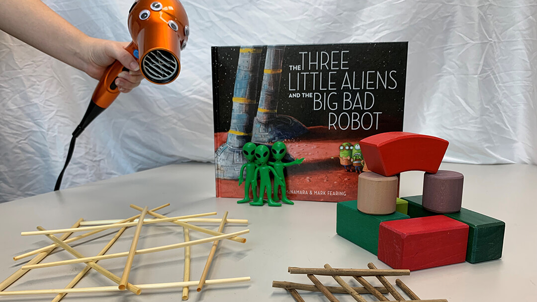 Three Little Aliens and the Big Bad Robot book on a table, along with objects representing items from the book.