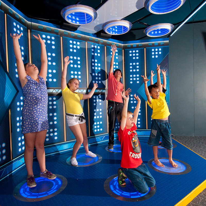 Science Fiction, Science Future - five guests with arms upraised in Beam Me Up exhibit.