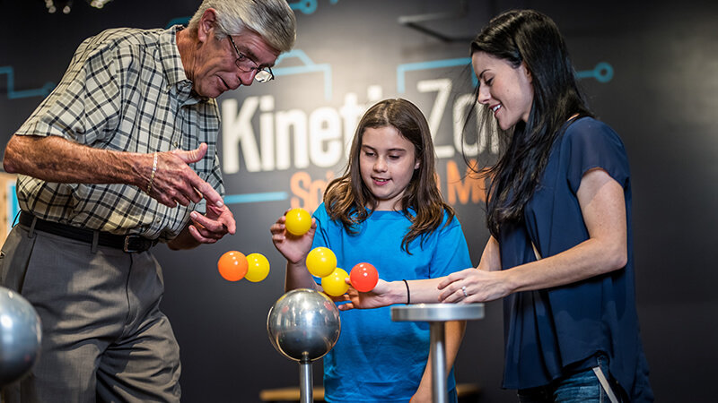 A family balancing plastic balls in the air with the air resistance exhibit.