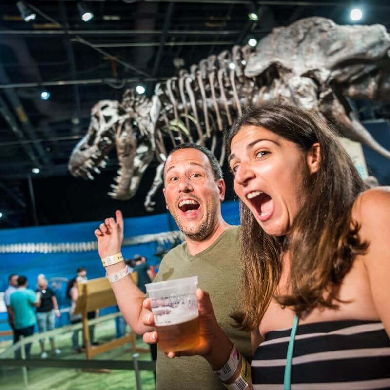 two people pretending to be scared in front of a t-rex