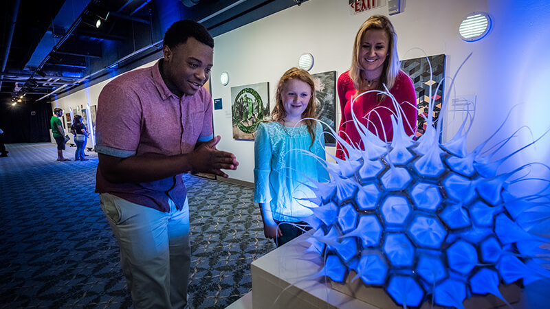 Guests reacting to a sculpture of a microorganism.
