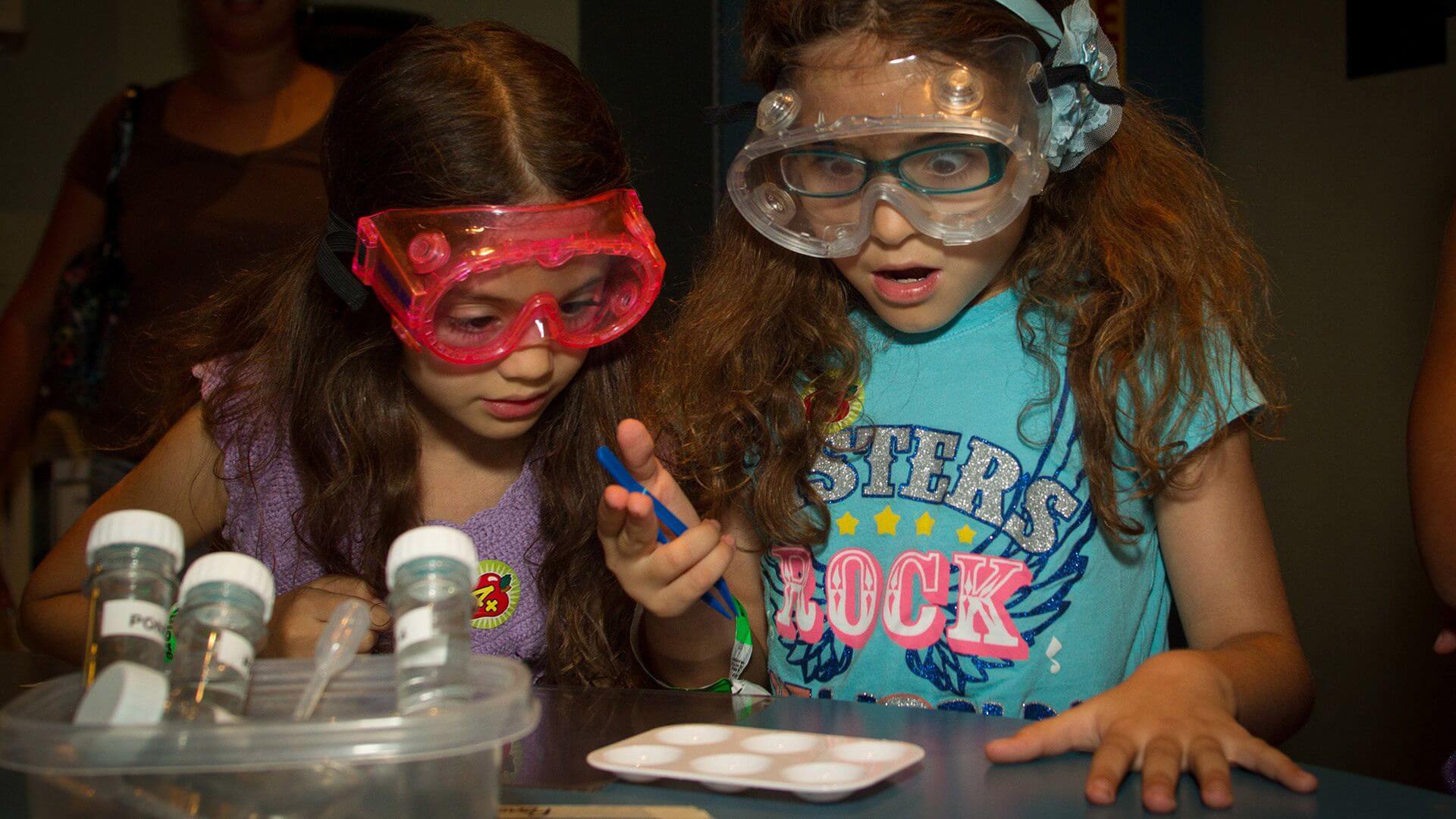 Two young girls in awe of a science experiment they're working on