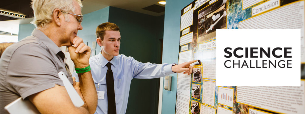 A high schooler explaining his research to a man at the Lockheed Martin Science Challenge.