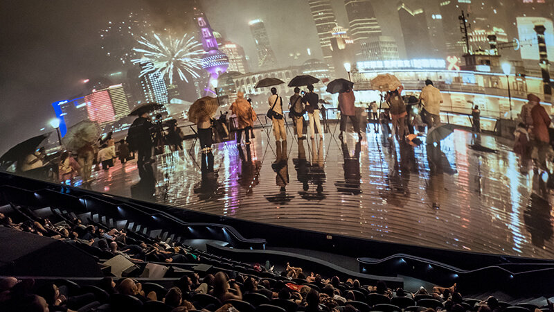 A giant-screen movie showing an image of people on a city street.