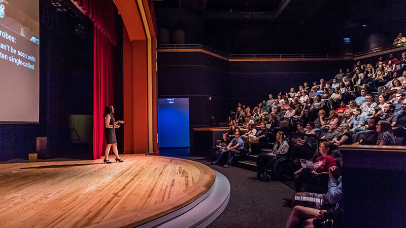 Guests listening to presenter on stage of Digital Adventure Theater.