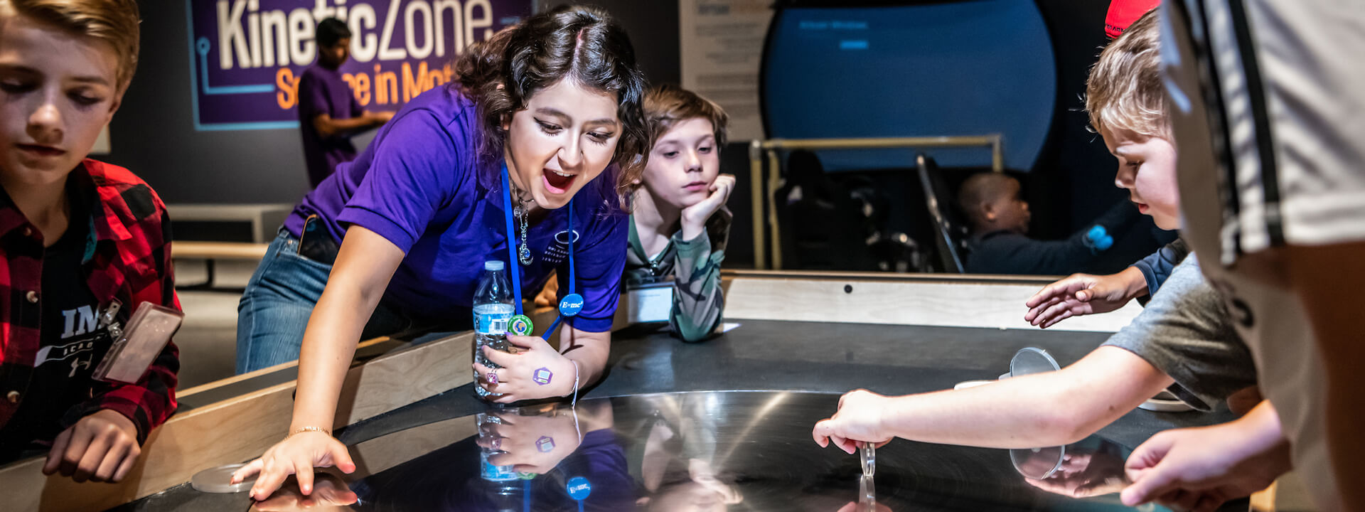 Excited OSC employee interacting with children on an exhibit table.