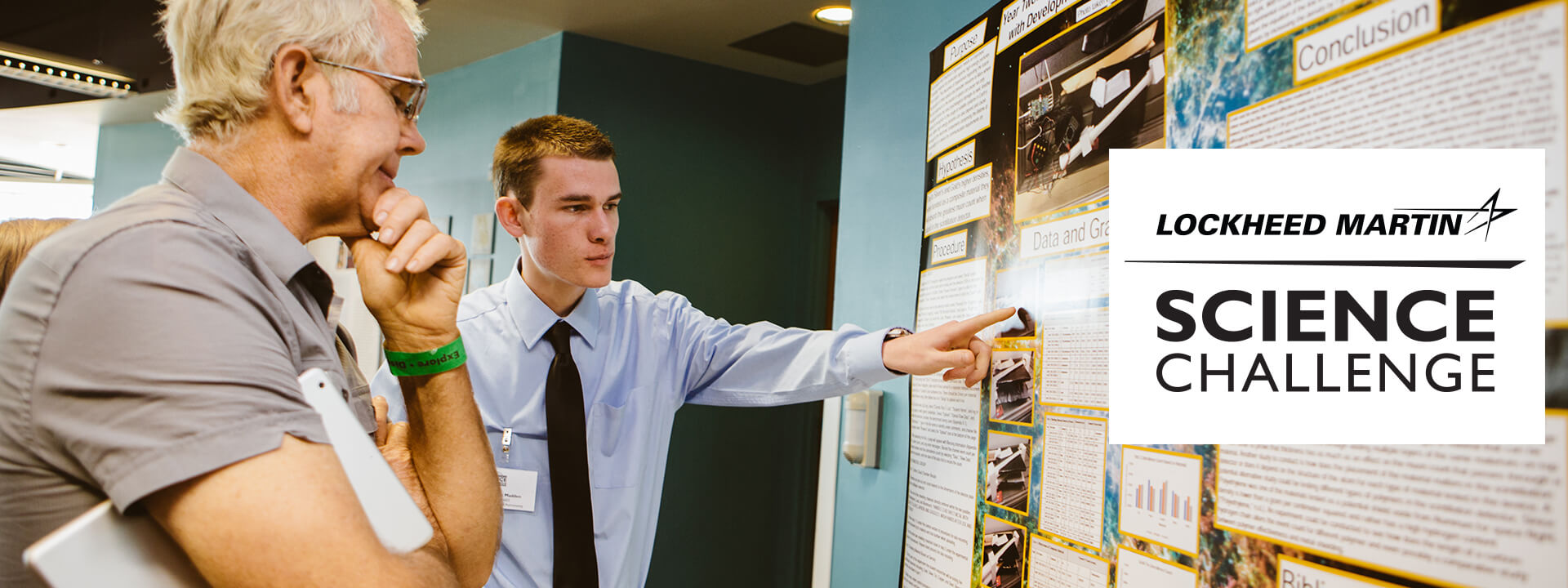 A high schooler explaining his research to a man at the Lockheed Martin Science Challenge.