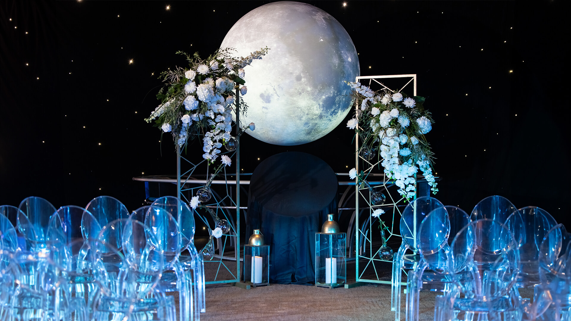 Unveil-August-2024-OSC-50-AI_1920x1080 Wedding aisle setup in Our Planet exhibit featuring star lights and beautiful clear chairs.