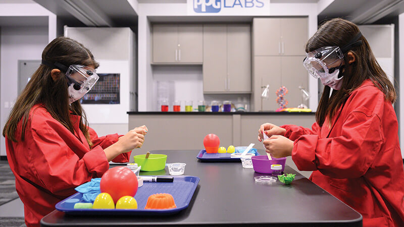 Photo of two Girl Scouts in lab gear performing experiments.