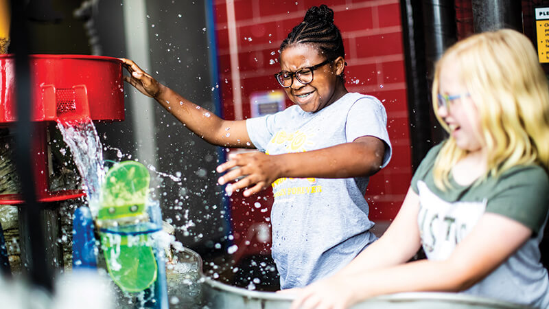Photo of two Girl Scouts interacting with a water exhibit.