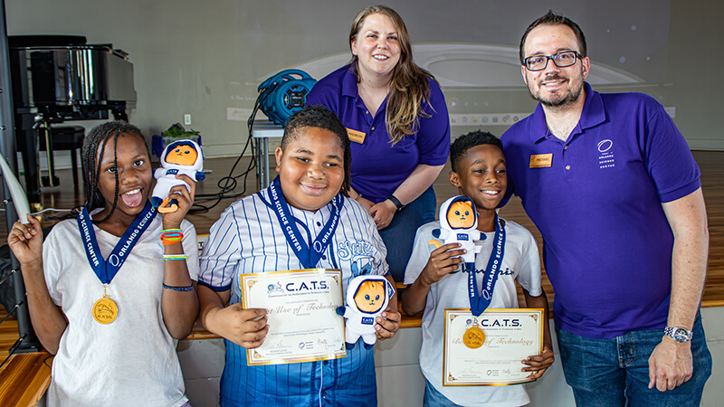 CATS-Winners_800x450 Three CATS Program Competition winners with their certificates, medals and stuffed animal mascots, along with two OSC educators.