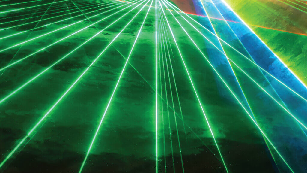 A fan of green lasers shine through a fog of smoke